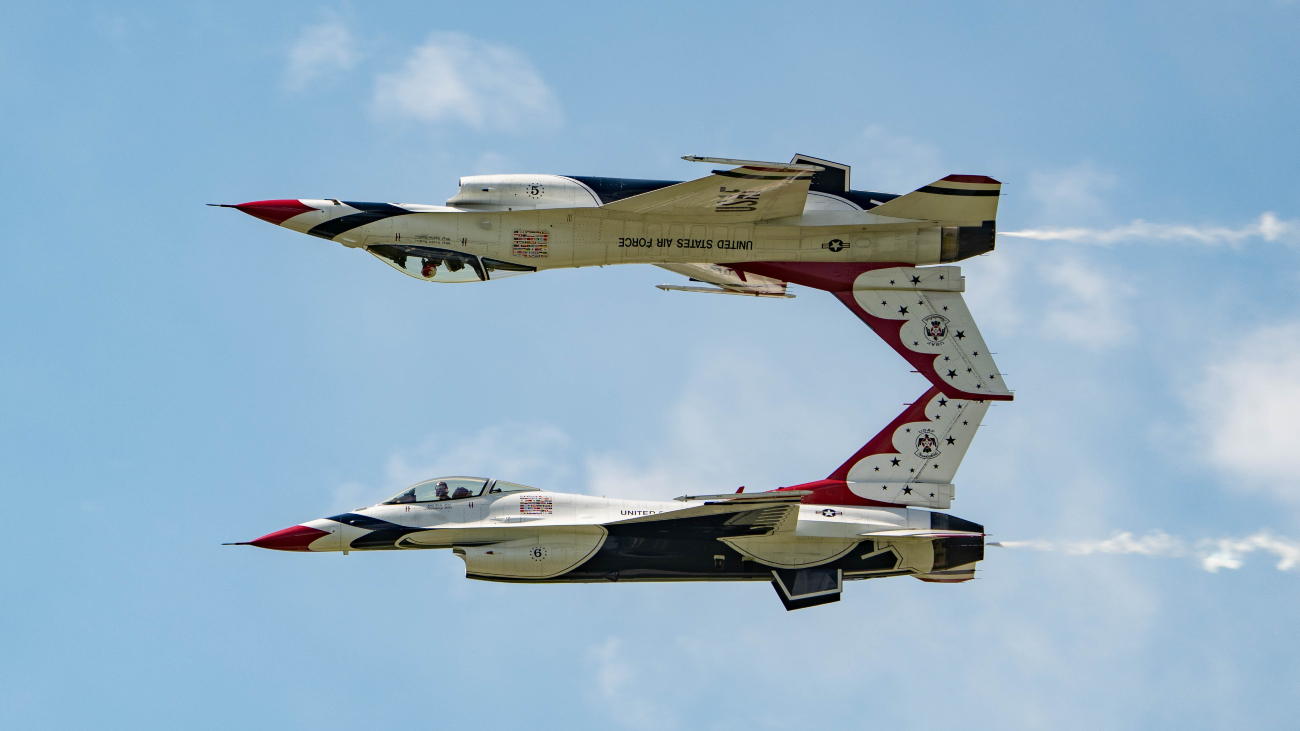 Twee F16s van de US Air Force vliegen met hun ruggen naar elkaar toe waardoor het lijkt alsof een van de twee een spiegelbeeld is.