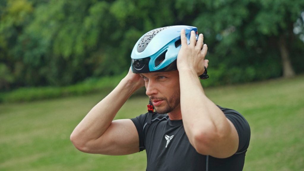 Fietser doet de fietshelm JY Smart Helmet op. 