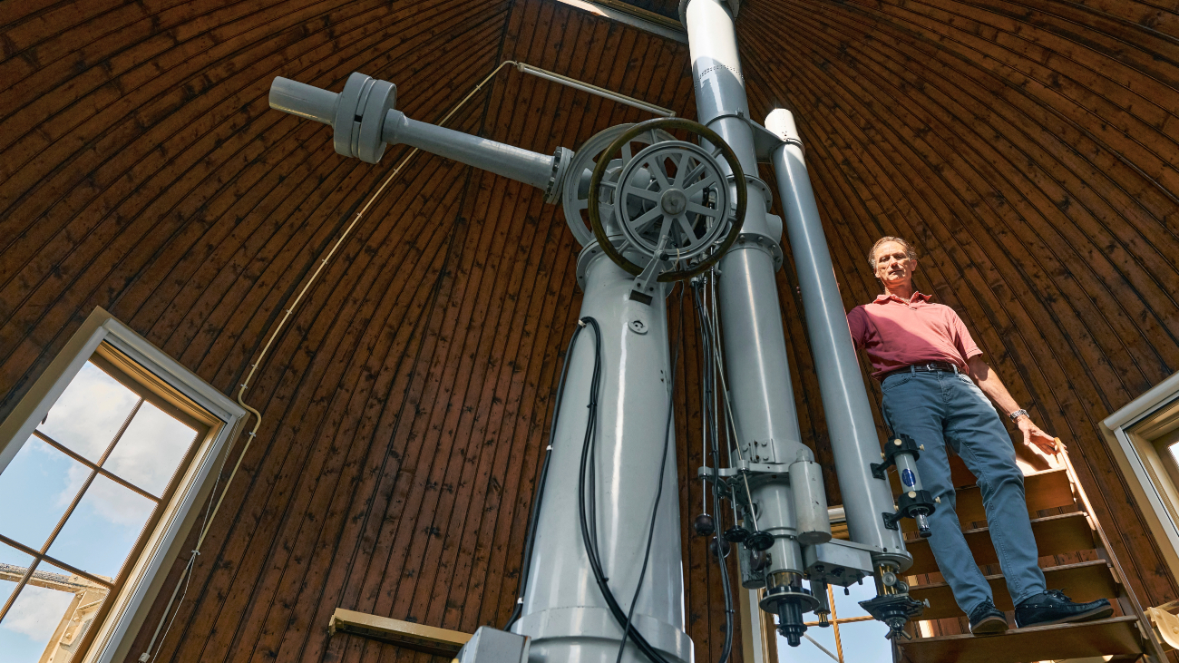 Koen Kuijken naast een telescoop waarmee hij onderzoek doet naar donkere materie