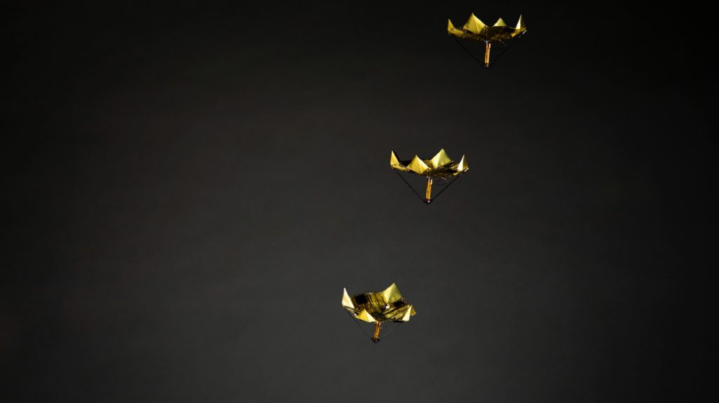 Drie gevouwen goudkleurige microfliers in de lucht op een donkere achtergrond