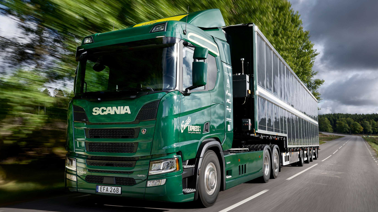 Groene Scania vrachtwagen met zonnepanelen aan de zijkant van de oplegger.