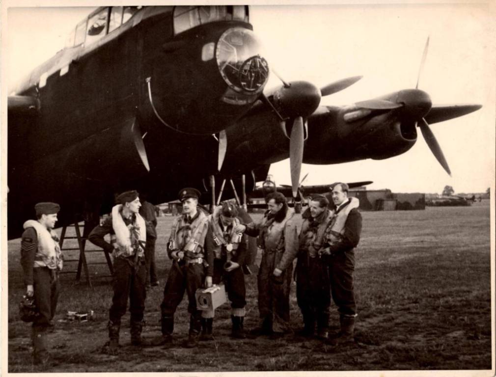 Zeven bemanningsleden staan voor een de Lancaster ED603.