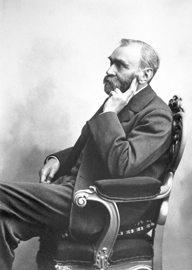 Alfred Nobel zit in een stoel en ondersteund zijn hoofd met z'n hand. 