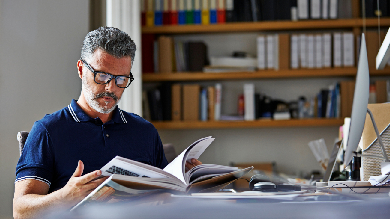 Man met bril leest een boek. Dragen slimme mensen vaker een bril?