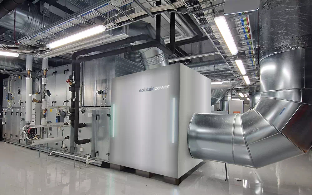 De HVAC-systemen worden aangesloten op zo'n CO2-capture-unit. Het is een zilverkleurige DAC-machine van ongeveer 3x3x3 meter waar grote buizen uit komen. 