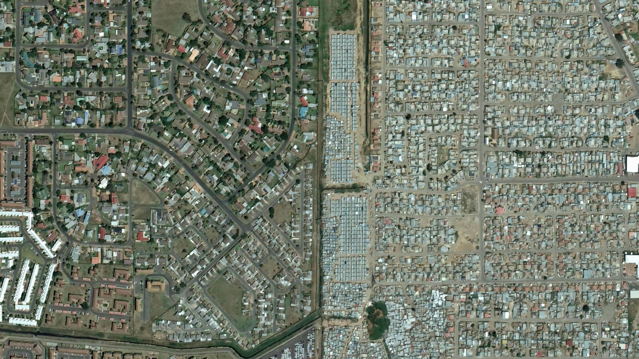 Satellietfoto laat sporen van de apartheid en ongelijkheid in Zuid-Afrika zien. De wijk links is ruim opgezet met veel groen, de wijk rechts is dicht op elkaar gebouwd met weinig groen.