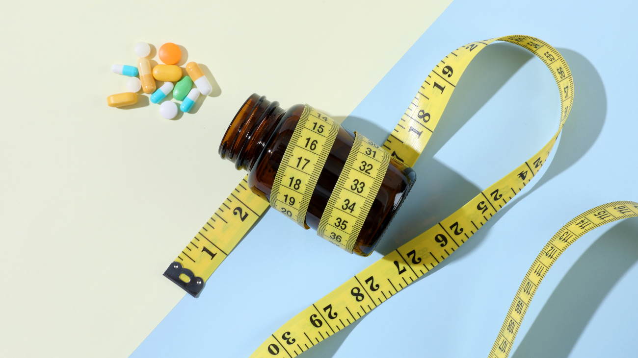Pillen naast een potje met meetlint eromheen. Obesitas pil is doorbraak van 2023