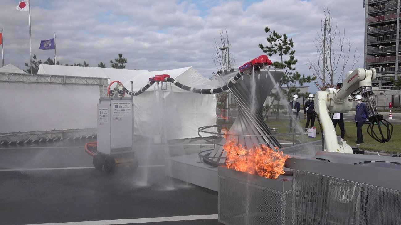 Een brandslang zweeft in de lucht door krachtige waterstralen die ook vuur proberen te doven.