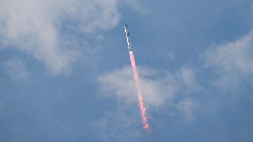 Starship vliegt door de blauwe lucht, een paar wolken. De raket laat een rood en vurig spoor achter