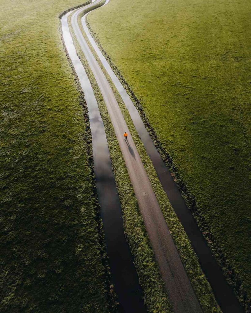 Een person op een weg door een polder