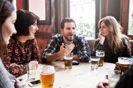 Mensen in kroeg praten met glazen alcohol op tafel