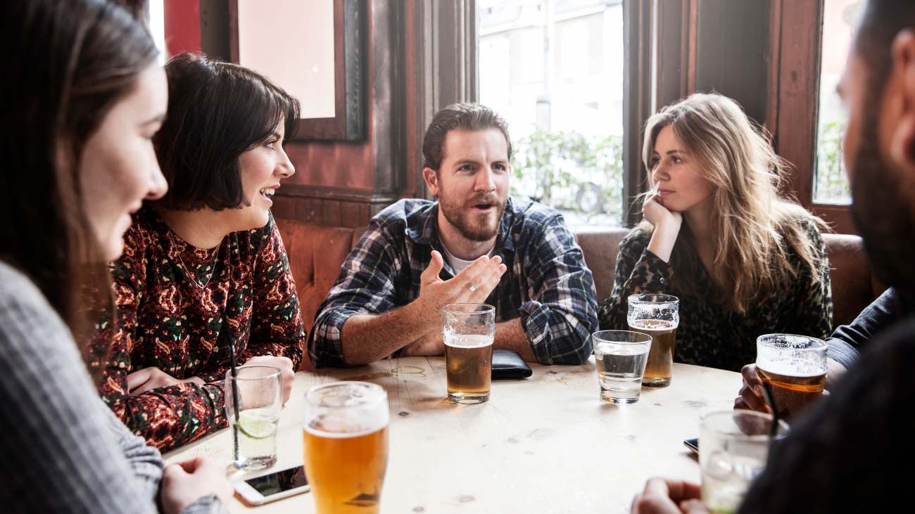 Mensen in kroeg praten met glazen alcohol op tafel