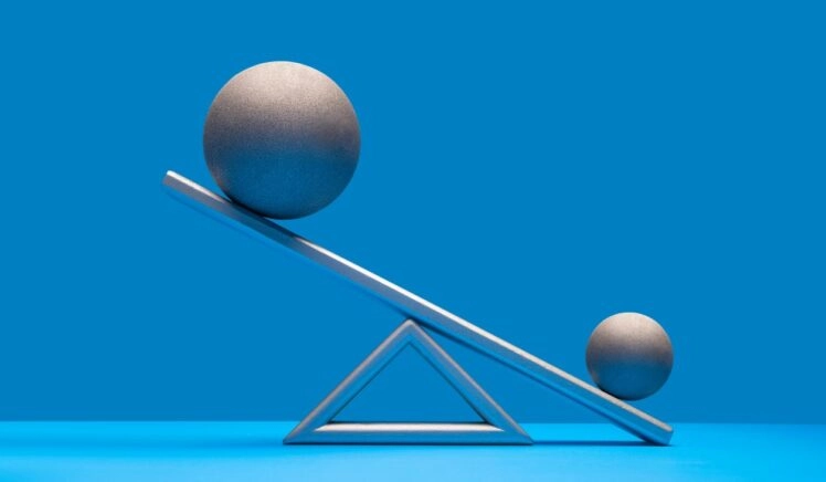 een wip met twee ballen erop, ter illustratie van de termen massa en gewicht