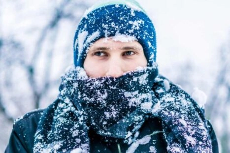 man in kou en sneeuw met muts op om te voorkomen dat hij warmte verliest via zijn hoofd