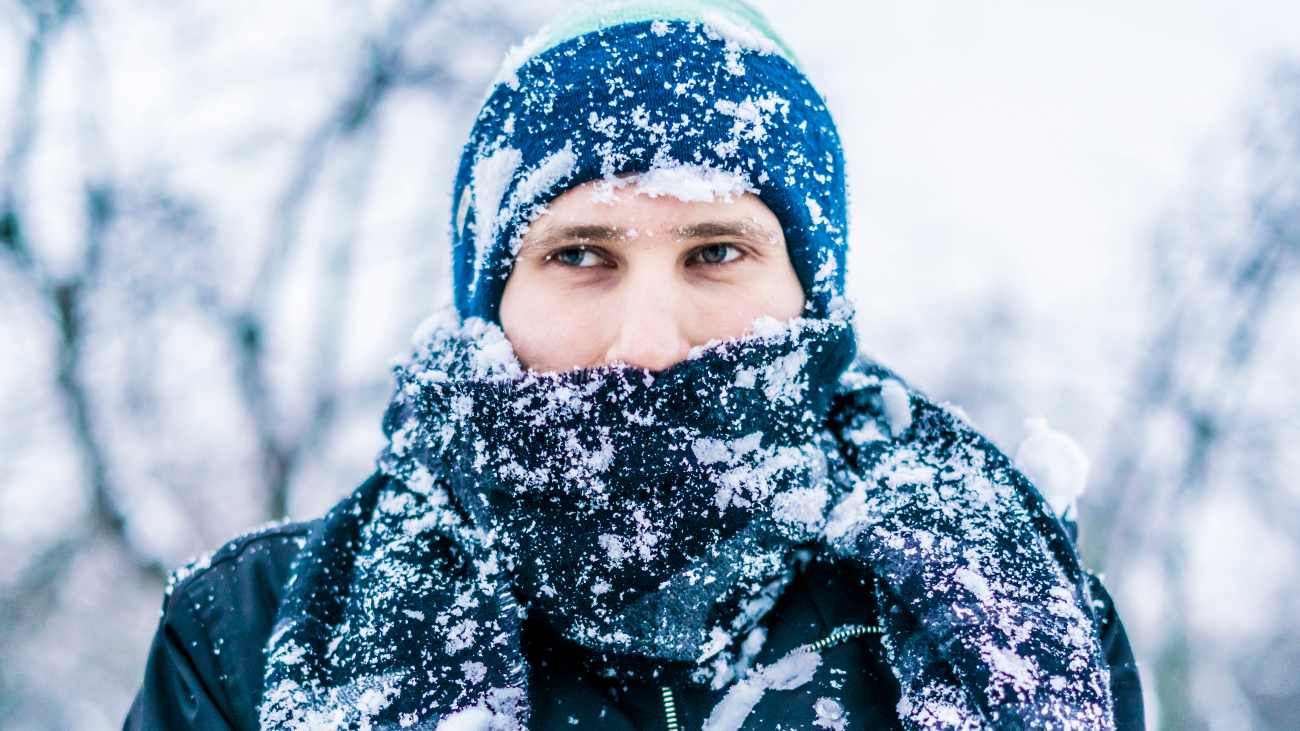 man in kou en sneeuw met muts op om te voorkomen dat hij warmte verliest via zijn hoofd