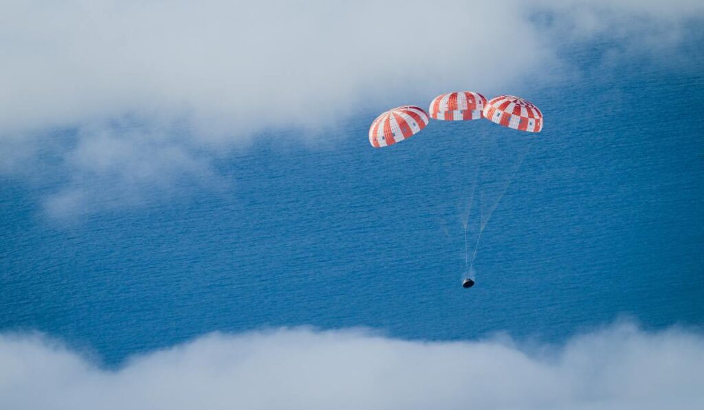 Het Orion-ruimtevaartuig van de Artemis I-missie wordt met grote parachutes afgeremd voordat het in de oceaan plonst