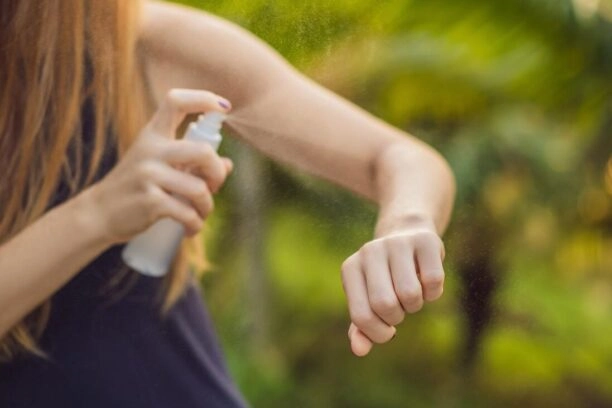 Vrouw spuit DEET op haar arm