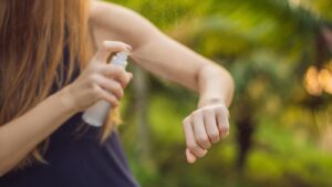Vrouw spuit DEET op haar arm