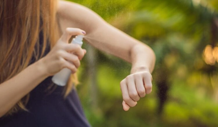 Vrouw spuit DEET op haar arm