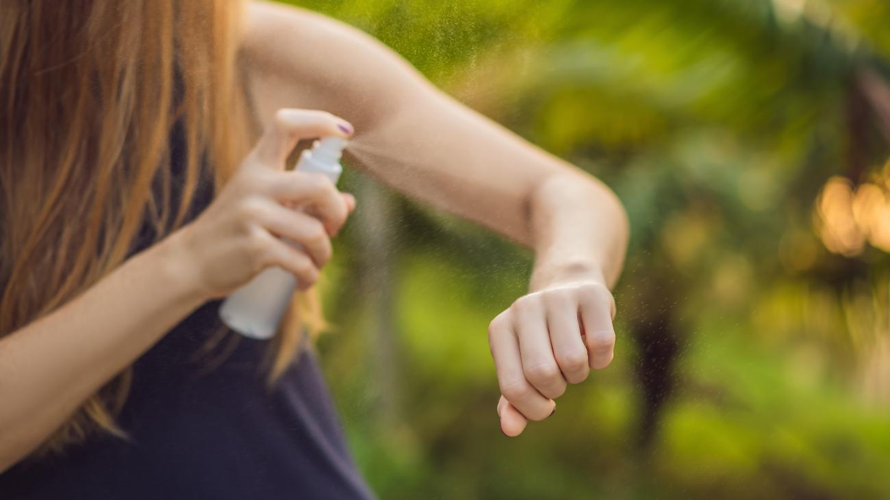 Vrouw spuit DEET op haar arm