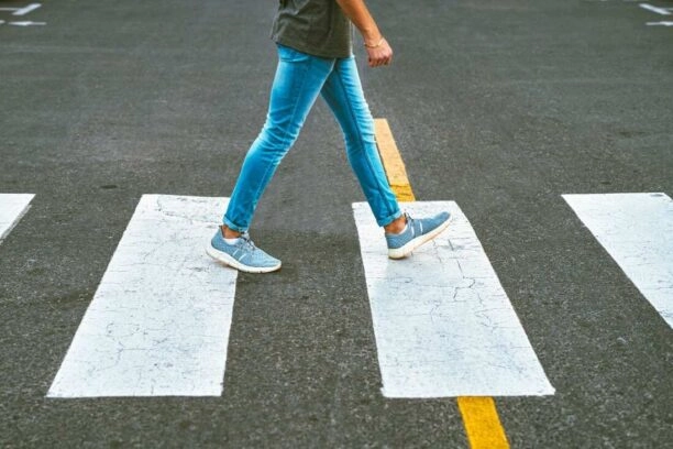 Onherkenbare man loopt over zebrapad en landt op zijn hak