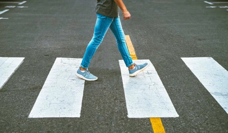 Onherkenbare man loopt over zebrapad en landt op zijn hak