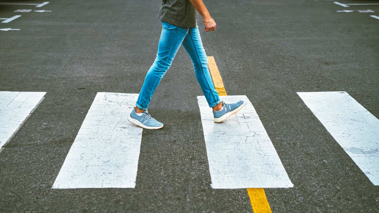 Onherkenbare man loopt over zebrapad en landt op zijn hak