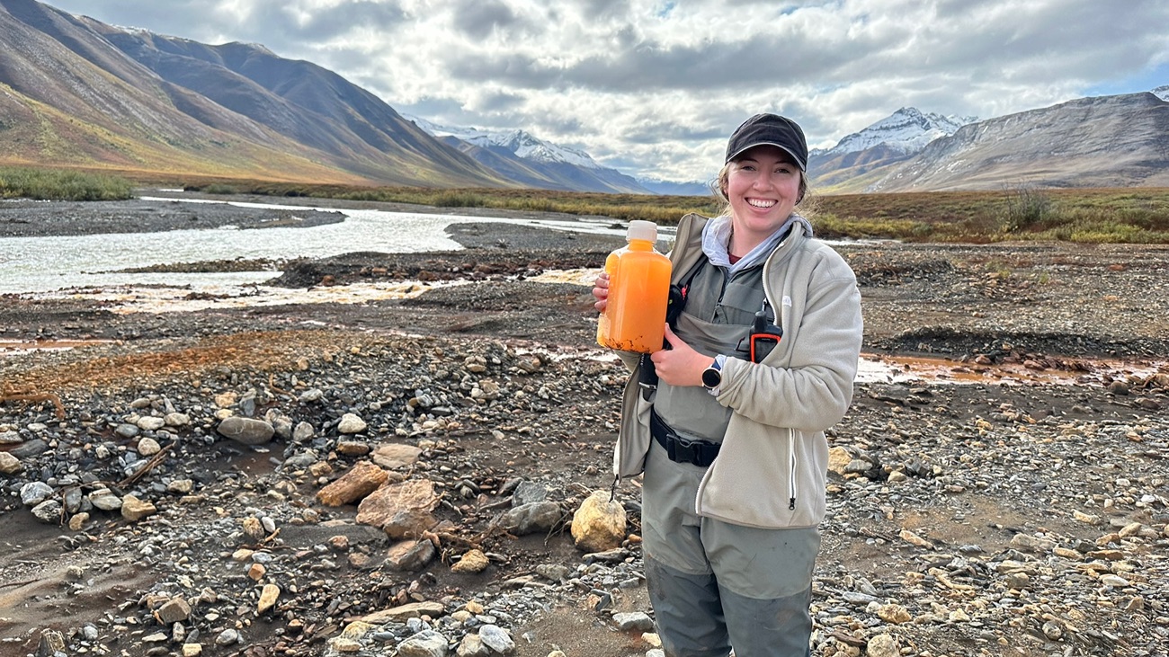 Een van de onderzoekers met een fles met oranje water uit de Igning River.